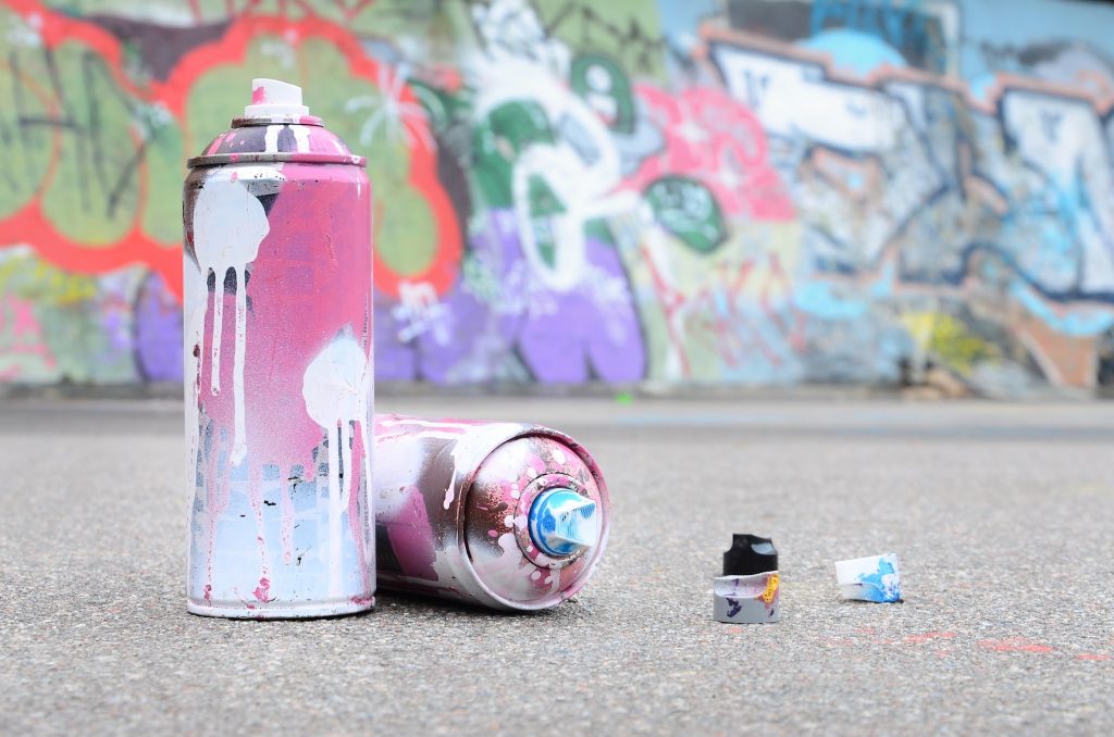 Several used spray cans with pink and white paint and caps for spraying paint under pressure is lies